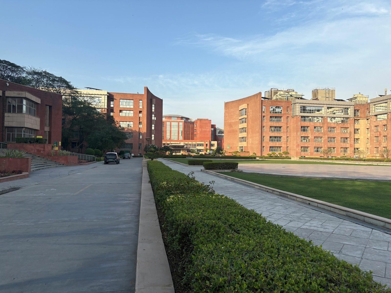 View of a modern red-brick educational campus in India during daytime, showcasing architecture and greenery.