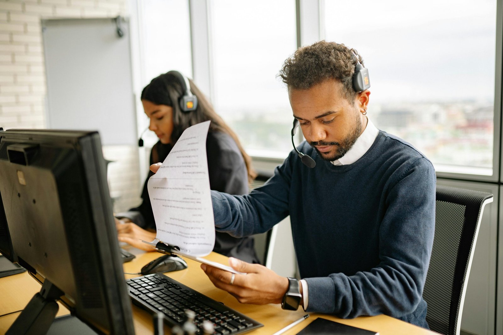 gas-pipeline Call center agents with headsets working in a modern office setting, reviewing documents.
